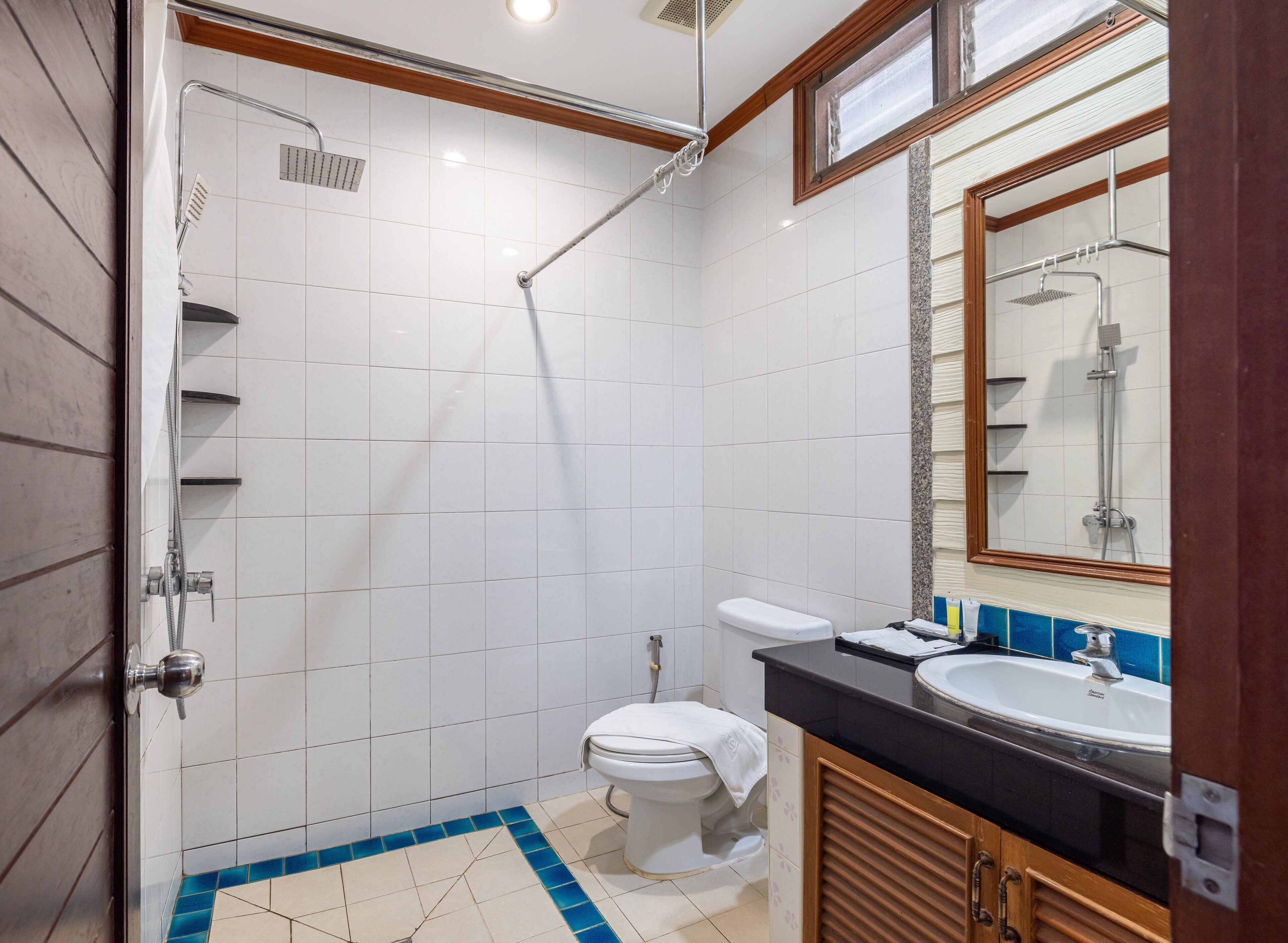 A bathroom with a shower, toilet, sink, and mirror.