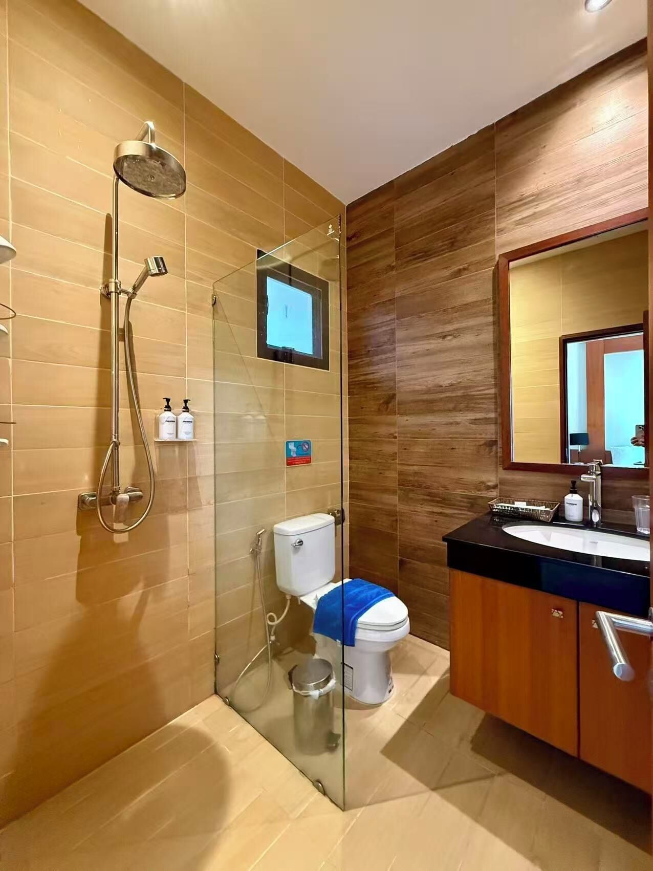 A modern bathroom with a glass-enclosed shower, a toilet, and a sink with a mirror.
