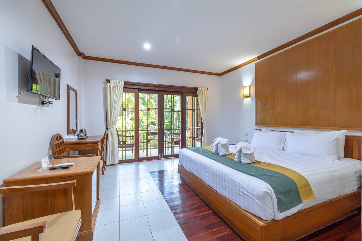 A hotel room with a bed, desk, chair, TV, and a view of the outdoors.