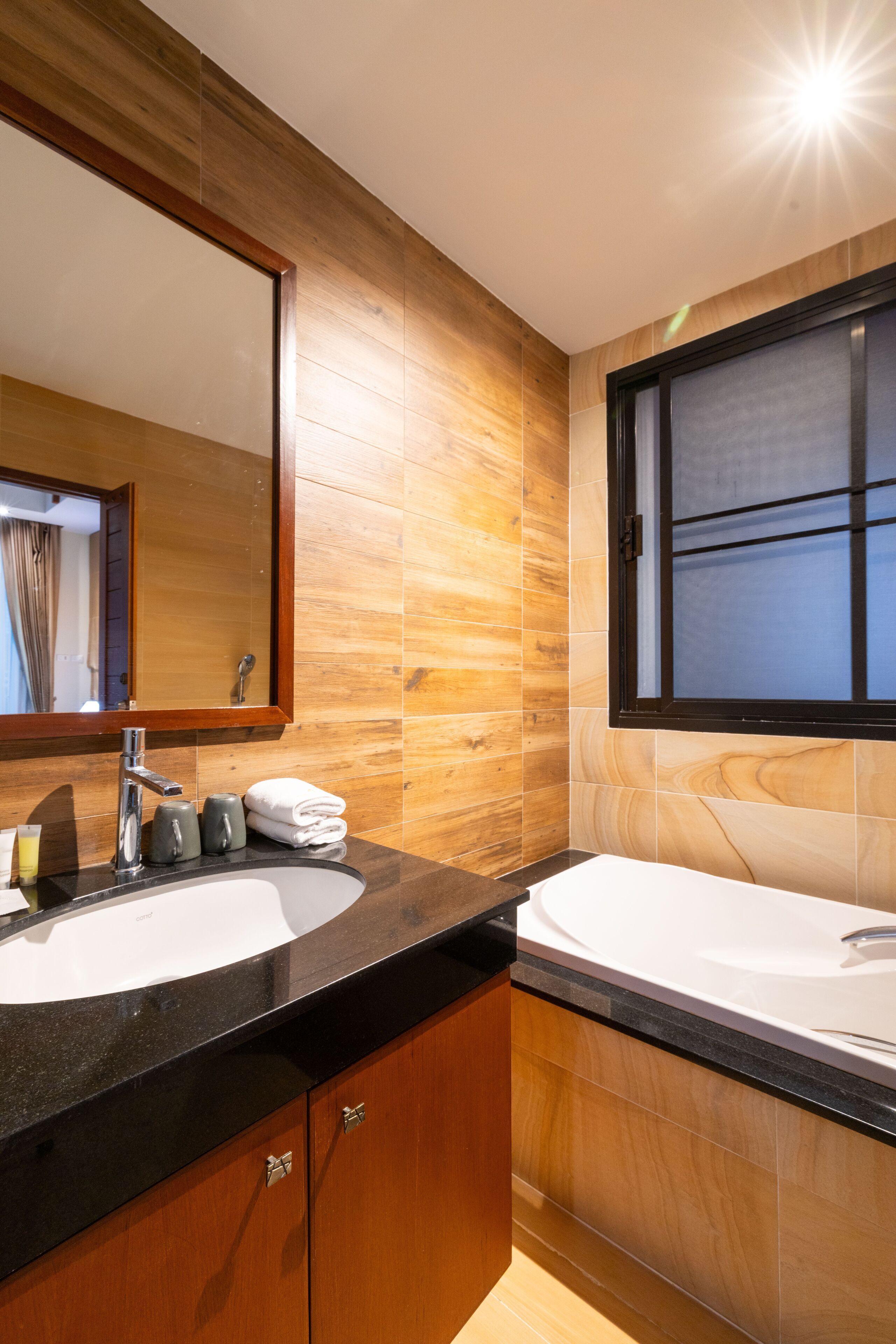Un baño moderno con dos lavamanos, paneles de madera y un espejo grande.