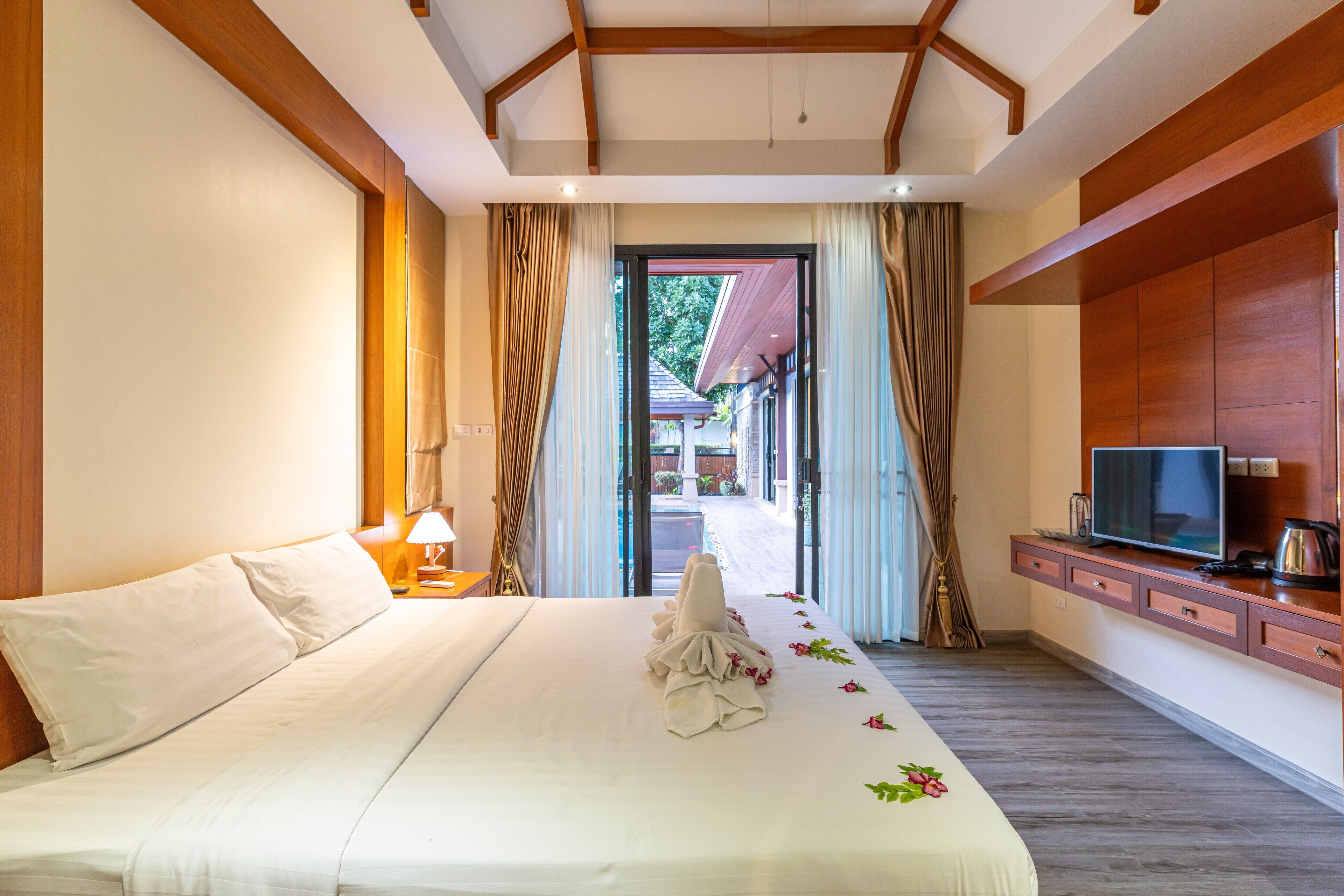 A hotel room with a large bed, a television, a coffee maker, and a view of the outside.