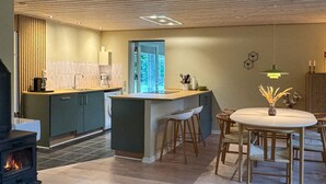 Eine moderne Küche mit einer zentralen Kochinsel, einem Essbereich mit rundem Tisch und einem Kamin.