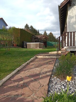 A stone pathway leading to a wooden structure with a pergola, surrounded by a well-maintained lawn and garden. - Gîte "chez Tony" (Lautenbach)