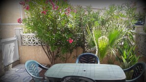 A patio with a table and chairs, surrounded by plants and a decorative wall.