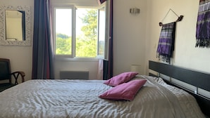Une chambre à coucher avec un lit, une fenêtre, une chaise et une lampe fixée au mur.