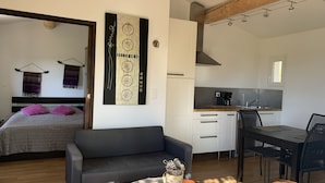 Un espace de vie compact comprenant un lit, un canapé, une kitchenette et un coin repas.