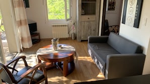 Un salon chaleureux avec une table basse en bois, un canapé gris et un téléviseur posé sur un meuble.