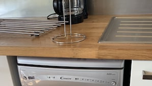 Une cuisine équipée d’un lave-vaisselle en acier inoxydable, d’une machine à café et d’un plan de travail en bois.