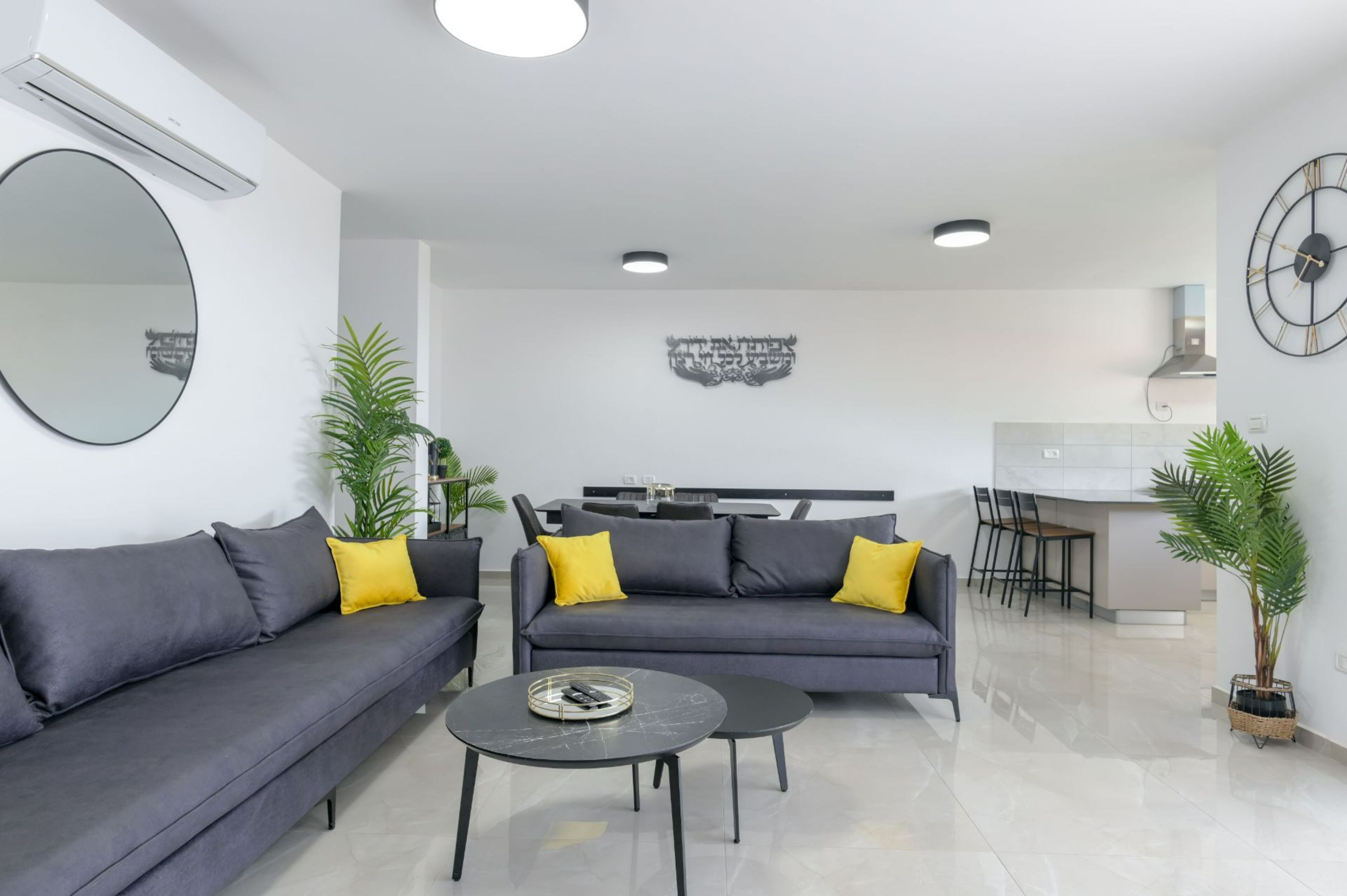 Una sala de estar moderna con un sofá gris, una mesa de centro y una zona de comedor con sillas y una mesa.