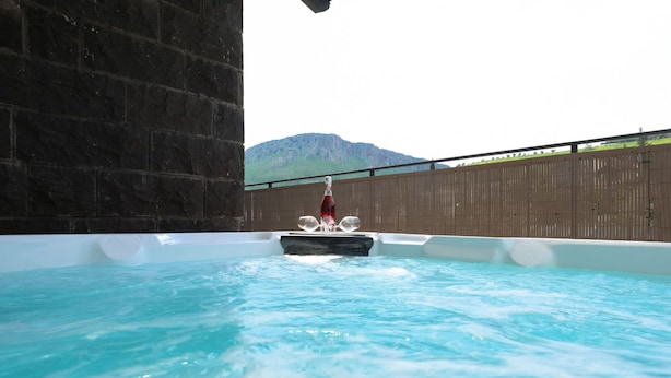 A hot tub with a person in a red outfit, surrounded by a wooden fence and a mountain in the background. - YalaRent Villa lumièra with Private Pool (Migdal)