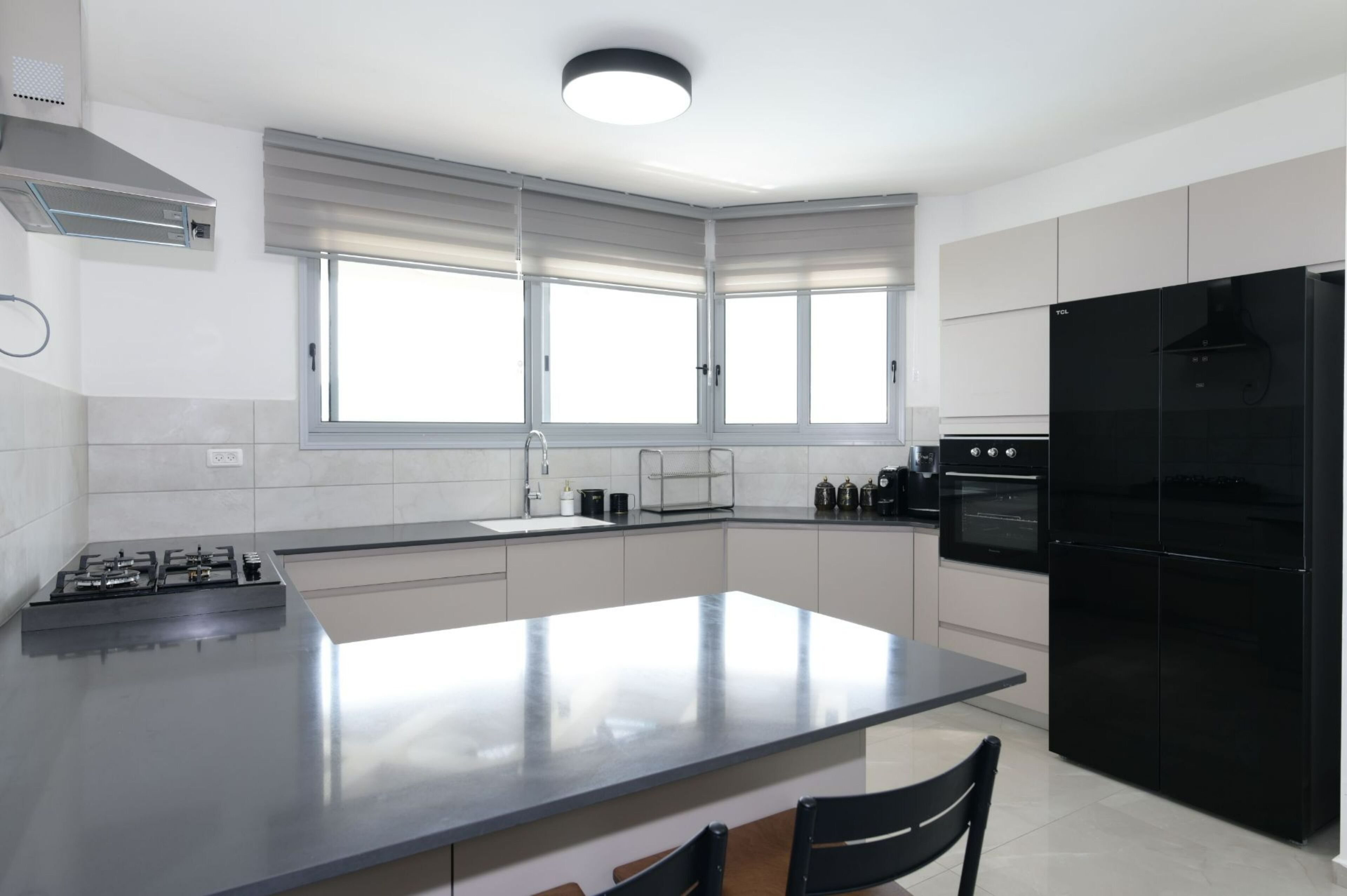 Una cocina moderna con una isla central, un refrigerador negro y una estufa a gas.
