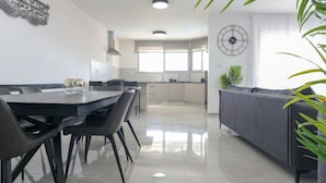 A modern kitchen with a dining area, a sofa, and a clock on the wall. - YalaRent Villa lumièra with Private Pool (Migdal)