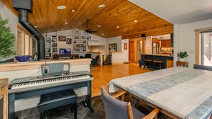 A spacious living area with a piano, a dining table, and a kitchen in the background. - Prosser Paradise_Hot Tub, Arcade, Walk 2 Prosser Reservoir, Exercise Equip, Kid Toys & Air Purifiers (Truckee)
