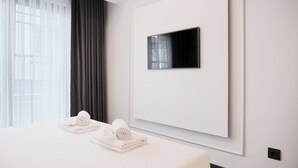 A modern hotel room with a large bed, a flat-screen TV mounted on the wall, and a window with sheer curtains. - Persona Hotel Galata (Istanbul)