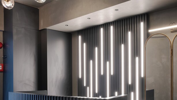 A modern reception desk with a sleek, dark finish and vertical light accents. - Persona Hotel Galata (Istanbul)