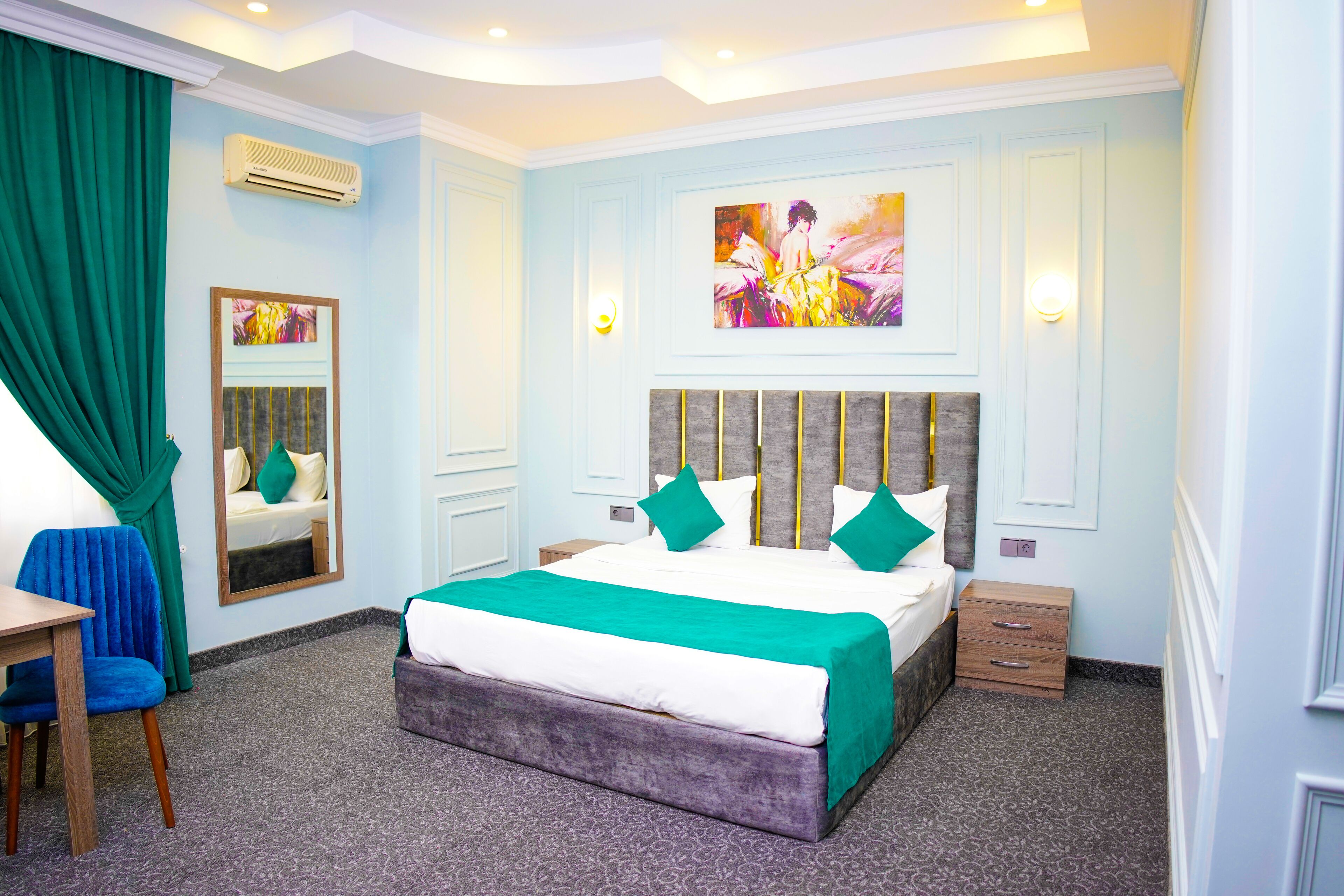 A bedroom with a large bed, a desk, a chair, a dresser, and a mirror.