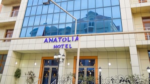 Un moderno edificio di un hotel con facciata in vetro e la scritta "ANATOLIA HOTEL" ben visibile.