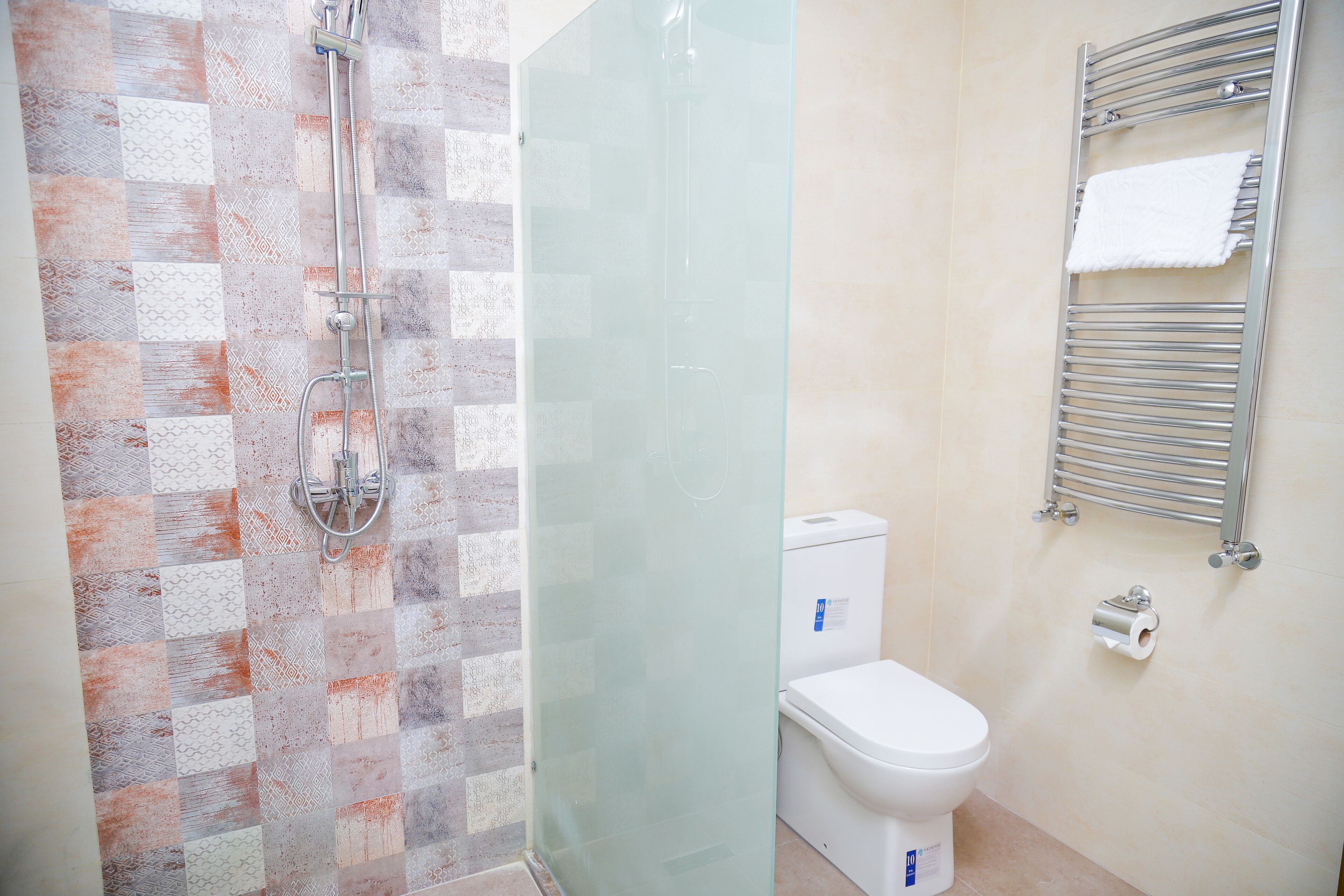 Un baño con ducha, inodoro y perchero para toallas.
