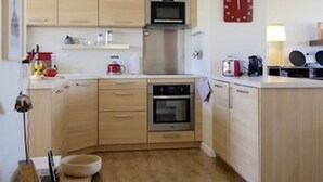 Ett kompakt kök med träskåp, en mikrovågsugn, en ugn och ett handfat.