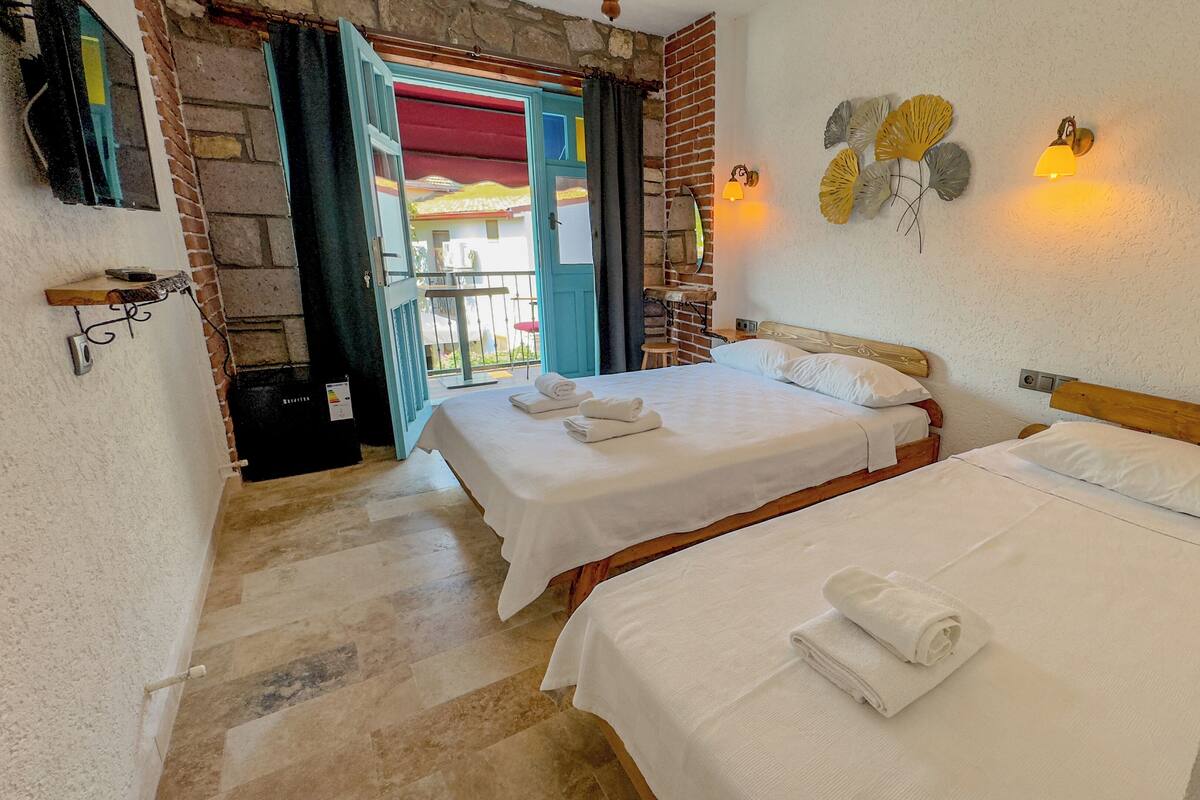 Habitación de hotel con dos camas, un balcón y vistas al exterior.