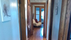 Un pasillo de madera que conduce a una sala de estar con un sofá y un ventanal.