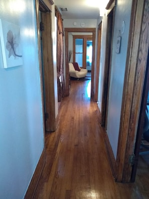 Un corridoio in legno che conduce a un soggiorno con un divano e una finestra.