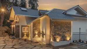 A modern house with a stone facade, a sloped roof, and a stone pathway leading to the entrance. - Echor Backwoods Villa Narkanda (Kumharsain)