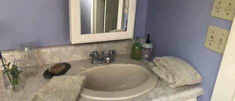 A bathroom with a sink, mirror, and toiletries.