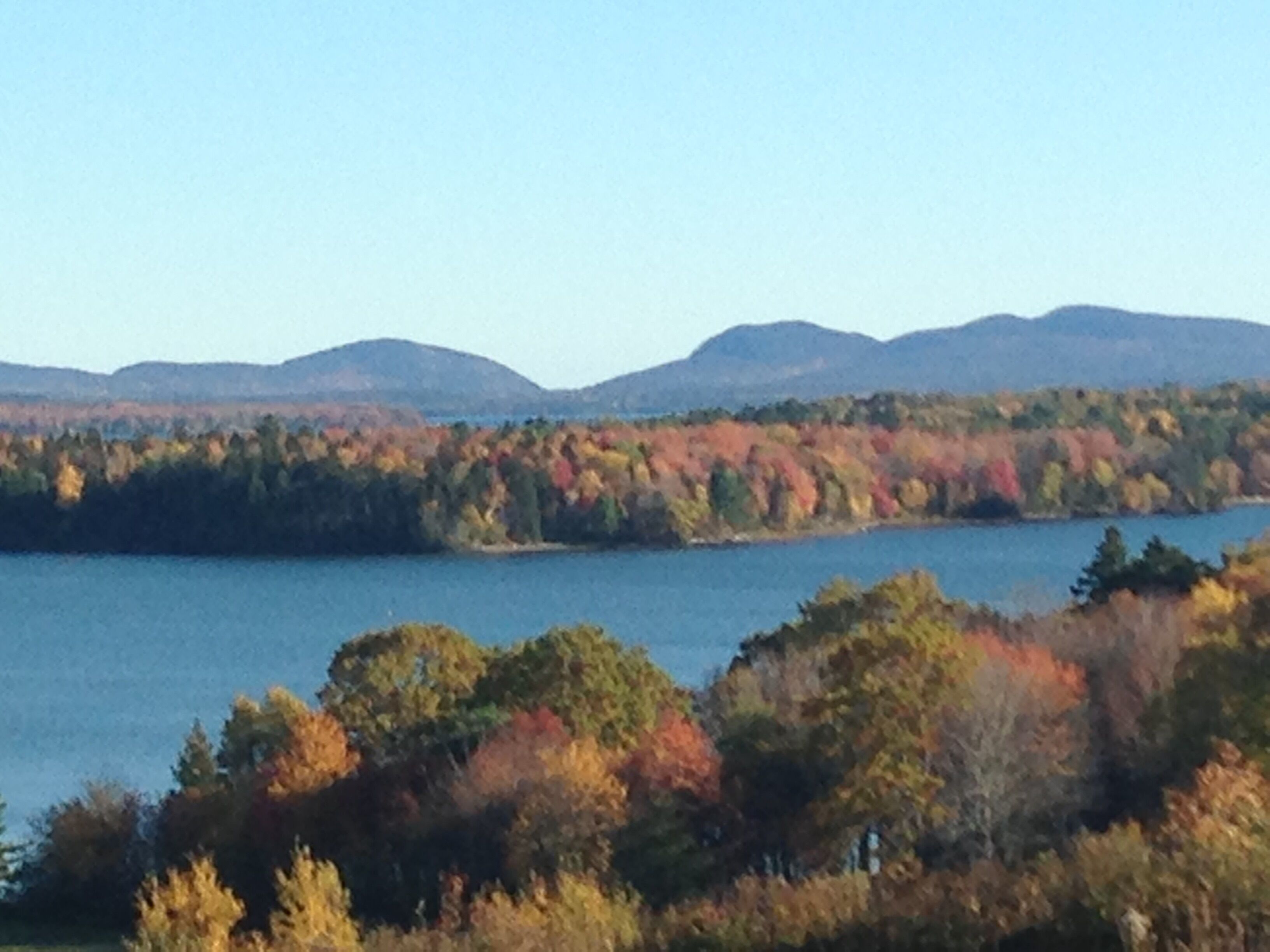 A lake surrounded by autumn-colored trees and distant mountains.