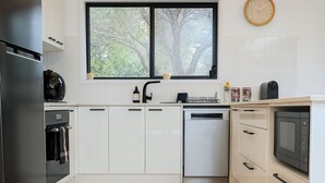 Een moderne keuken met witte kastjes, een zwarte koelkast, een vaatwasser en een magnetron.