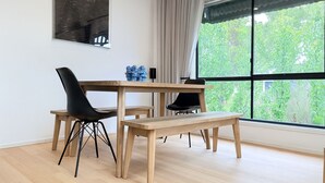 Een moderne eethoek met een houten tafel, zwarte stoelen en een bank.