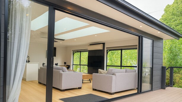 Een modern interieur met een glazen deur naar een zithoek met twee banken en een televisie.