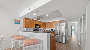 Une cuisine moderne avec des meubles en bois, un réfrigérateur en acier inoxydable et un coin bar avec des tabourets.