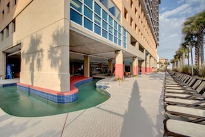 Un hotel con piscina, mobiliario exterior y una zona cubierta con vistas a la piscina.