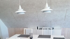 A dining area with a white table and chairs, a gray vase, and pendant lights. - 2 Bedroom Apartment in Bredstedt (Bredstedt)
