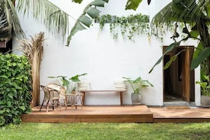 A patio area with wicker furniture, a bench, and potted plants.