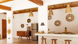 Una cocina moderna con una isla central, taburetes de madera, luces colgantes y platos decorativos en la pared.