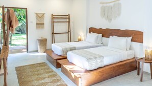 Un dormitorio con dos camas, una escalera de madera, un tapete tejido y una pequeña mesa con lámpara.