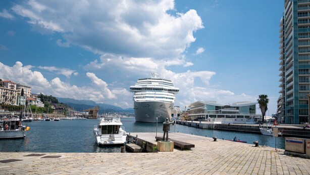 A cruise ship docked at a port with a modern building in the background. - [Luxury Savona] Cruises 1 min • Free WiFi • A/C (Savona)