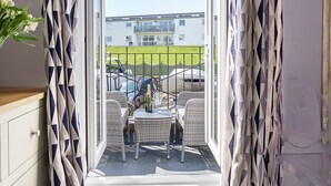 Una habitación con vistas a un balcón, una mesa con sillas y una botella de champán.