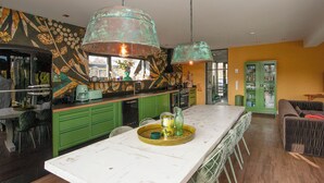 Una cocina moderna con armarios verdes, una isla blanca y una lámpara colgante de cobre.