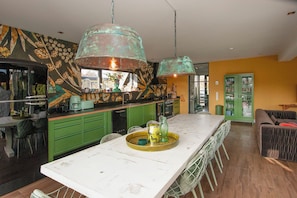 Una cocina moderna con armarios verdes, una isla blanca y una lámpara colgante de cobre.