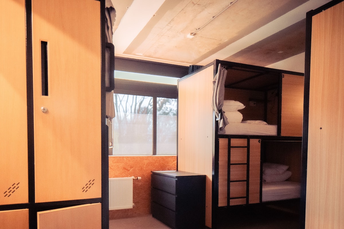 Une petite pièce avec des casiers en bois, un lit superposé et un radiateur.