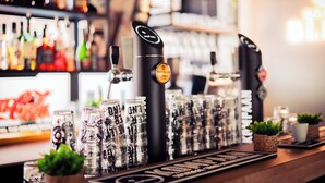 Una barra con grifo de cerveza, vasos y botellas.