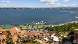 A coastal resort with a clear view of the sea, a swimming pool, and a dock with watercraft.