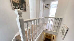 A staircase with white balusters and a handrail, carpeted steps, and a small rug at the bottom. - 37 Trenwith Place - a cottage that sleeps 5 guests in 3 bedrooms (St Ives)
