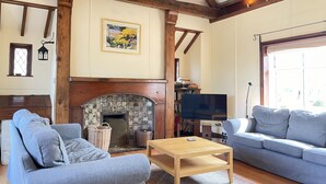 A cozy living room with a fireplace, two sofas, a coffee table, and a bookshelf. - Stratton Vow - a true 1920s Arts and Crafts house! (St Ives)