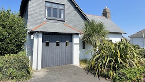 A two-story house with a grey roof, a garage door, and a chimney. - Stratton Vow - a true 1920s Arts and Crafts house! (St Ives)