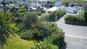 A residential street with houses, lush greenery, and a clear sky. - Stratton Vow - a true 1920s Arts and Crafts house! (St Ives)