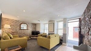 A living room with two sofas, a television, and a stone wall. - Treholme - a cottage that sleeps 6 guests in 3 bedrooms (St Ives)